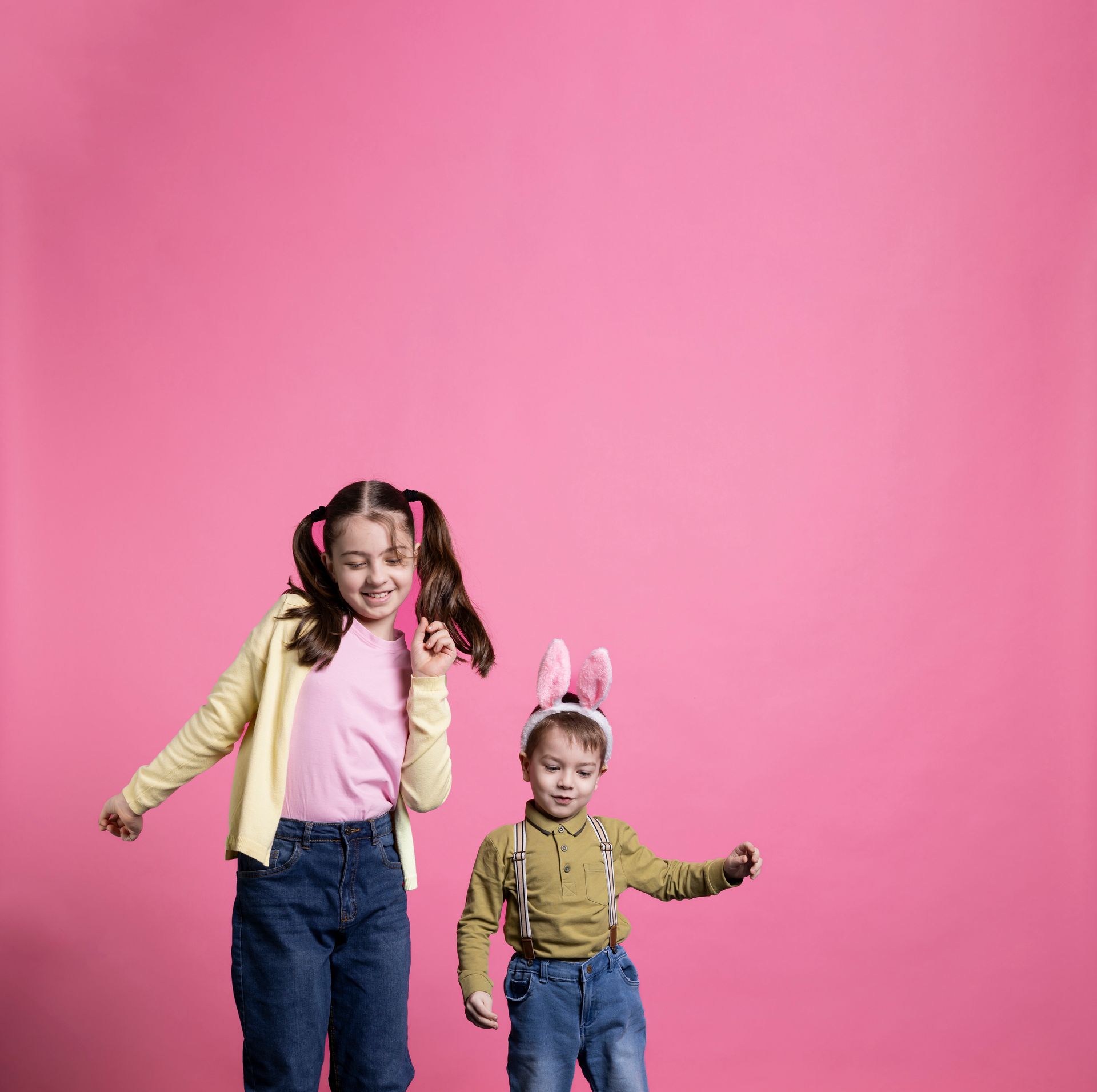 due bambini ballano davanti alla fotocamera, sfondo rosa