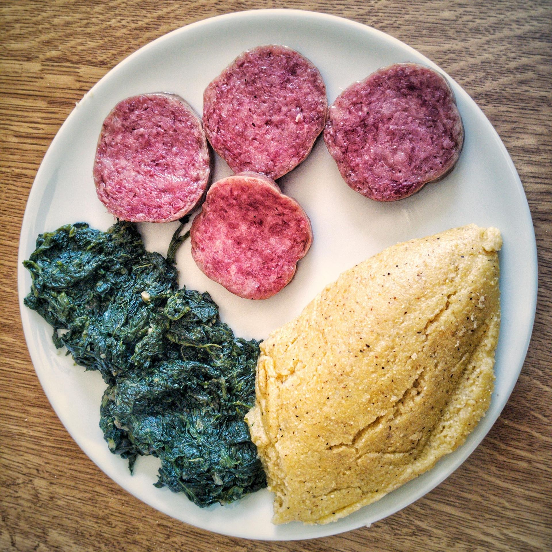 quattro fette di salame cotto servite con spinaci e polenta