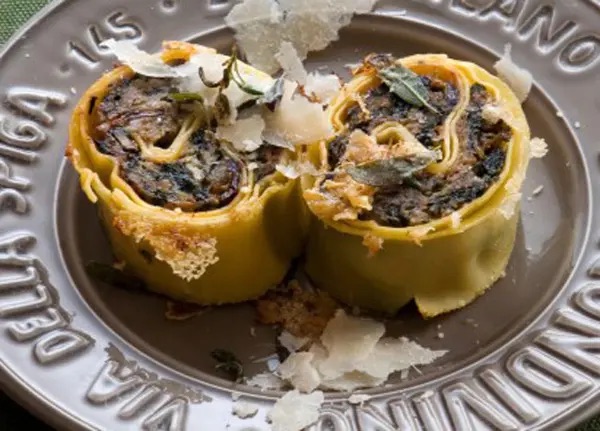 Due fette di salame di Borno, un primo piatto composto da pasta ripiena arrotolata e poi tagliata