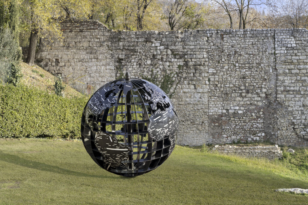 Scultura metallica su prato verde - Emilio Isgrò Mondo d'acciaio