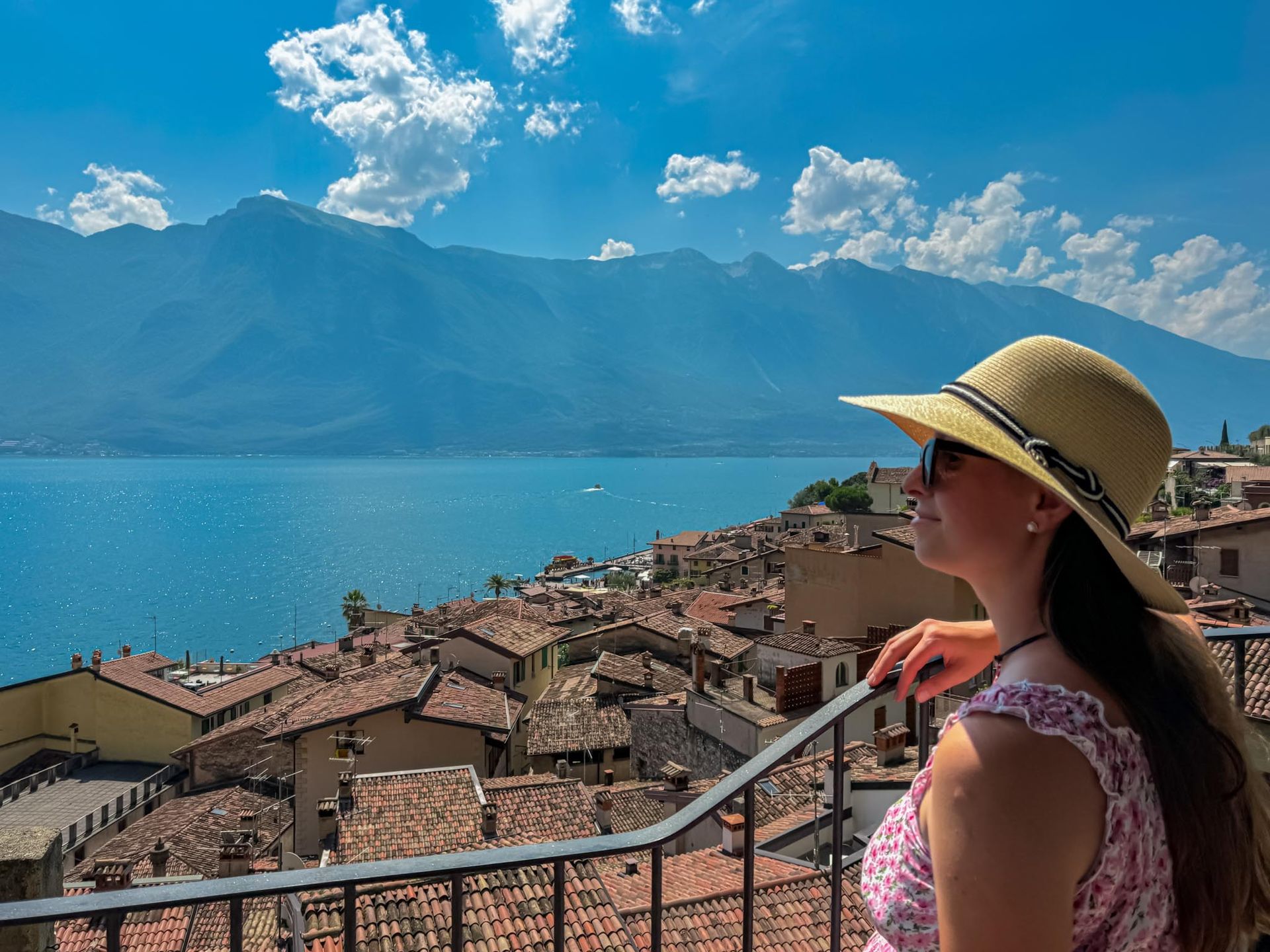Turista con cappello che guarda la meraviglia del lago di Garda