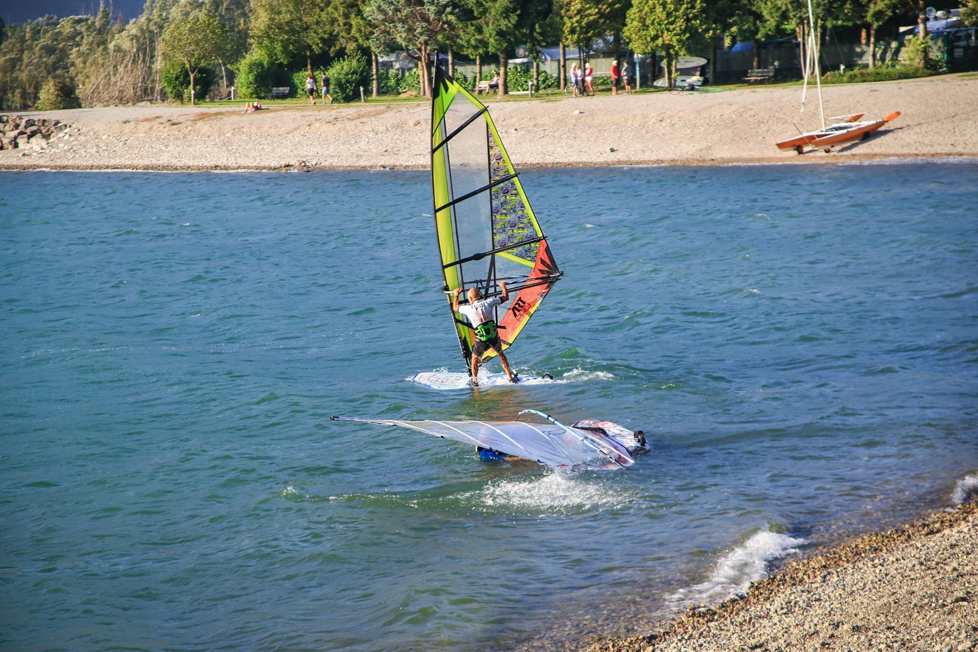 Windsurfista sul Lago d’Idro con vento e onde leggere tra le montagne della Valle Sabbia