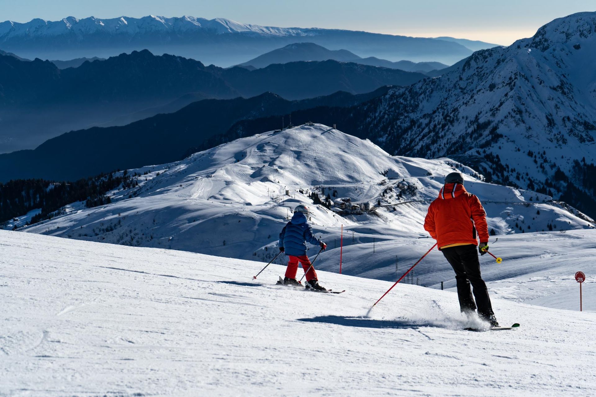 Sciatori sulle piste del Maniva in Val Trompia con panorama sulle montagne bresciane