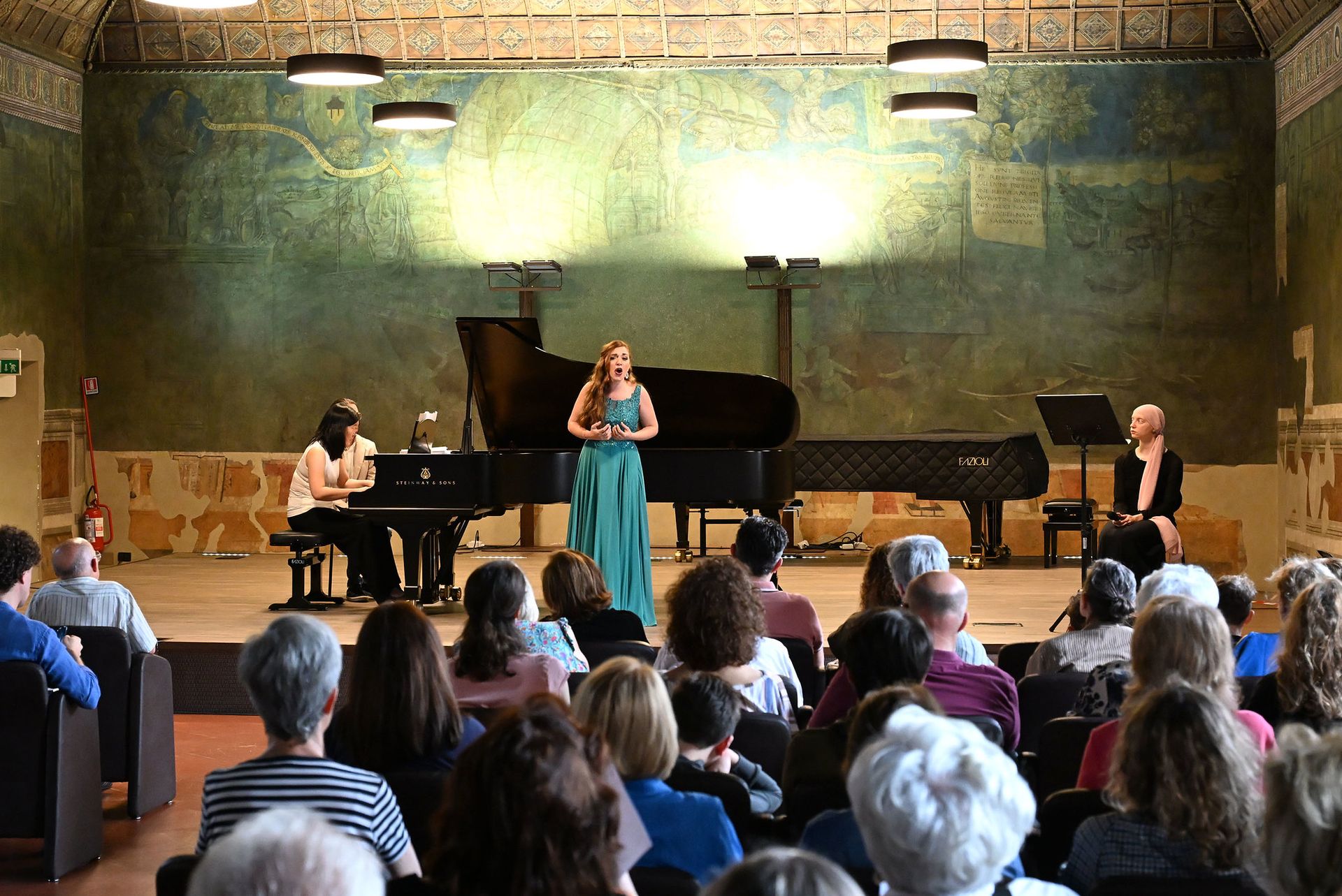 Cantante lirica su palcoscenico con pubblico di fronte a lei